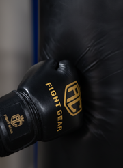Black boxing glove with 'FIGHT GEAR' branding on a dark background striking punch bag. 