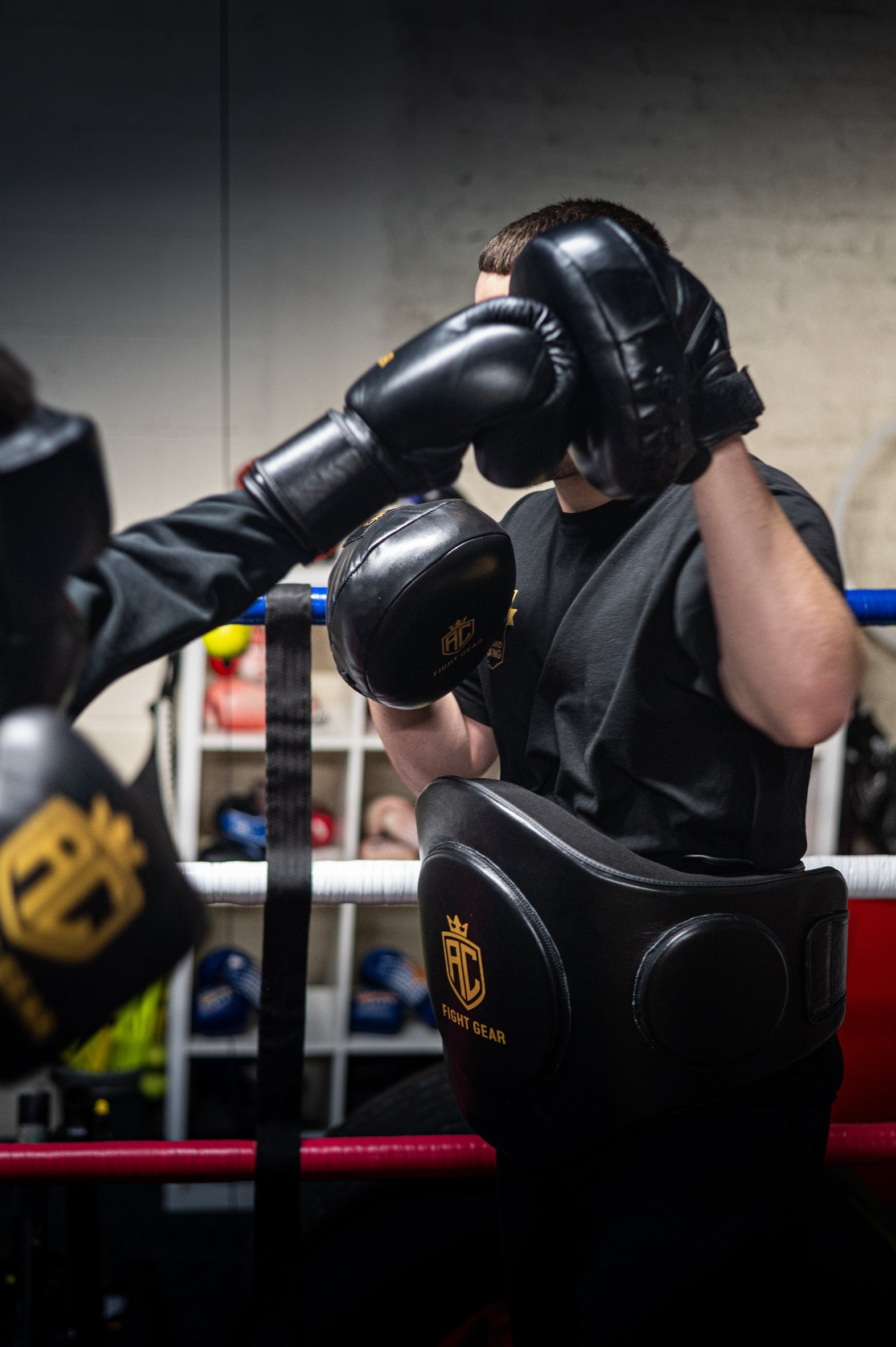 Person wearing boxing gloves in a boxing ring with another person.
